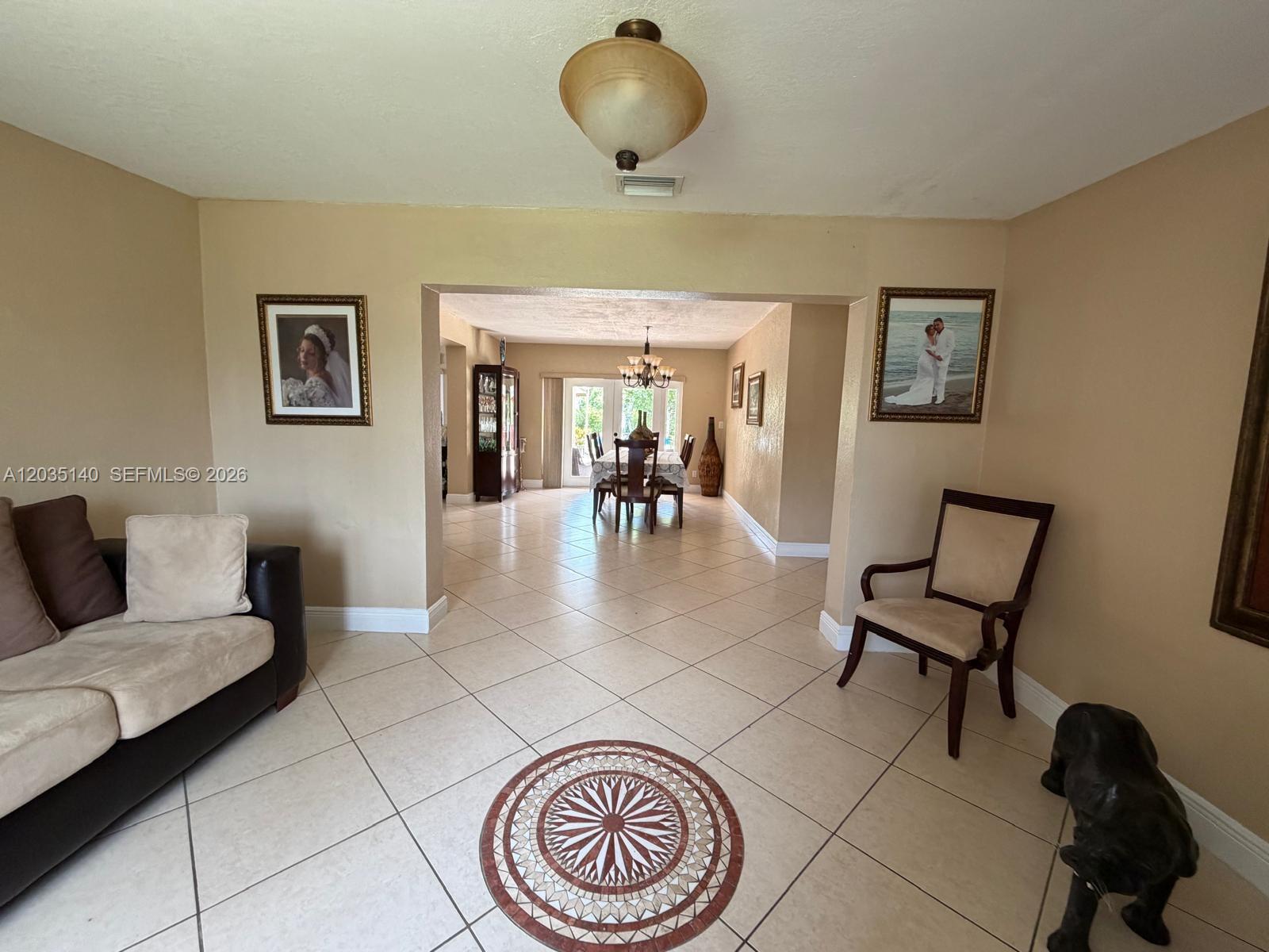 A living area with tile floors and a decorative medallion leads into a dining room — 17405 SW 109th Ct, Miami FL 33157, MIAMI, FL