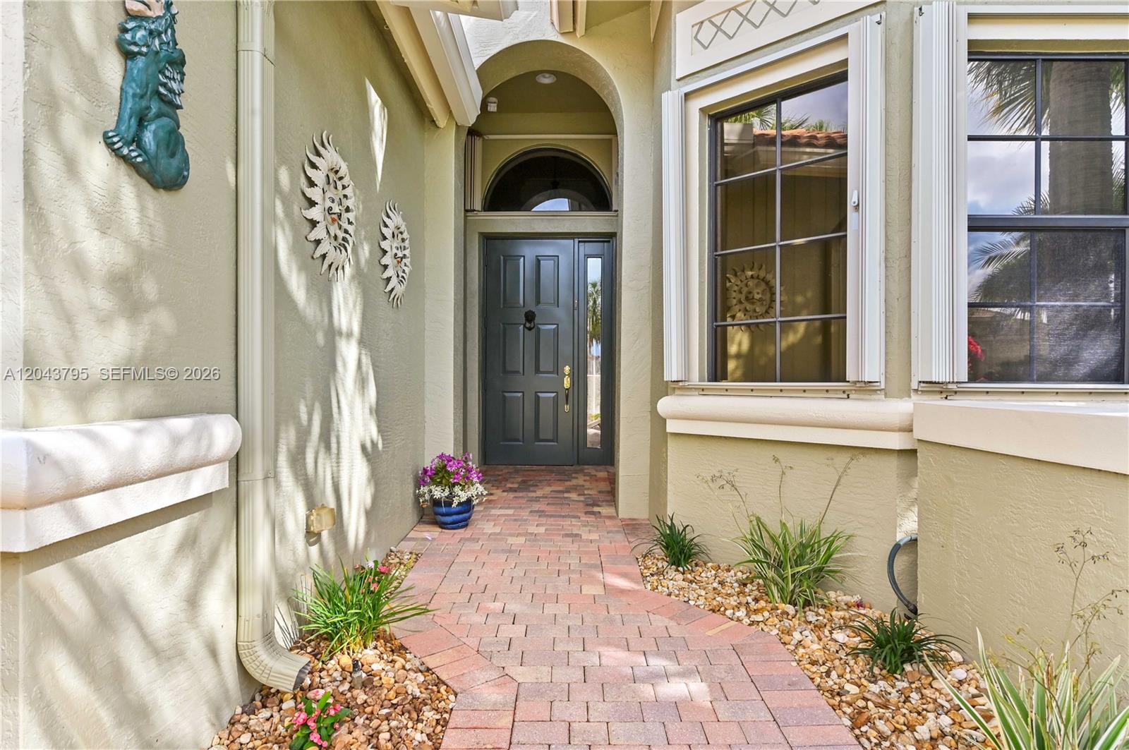 A brick walkway leads to a dark front door under an arched entryway — 6823 Fabiano Cir, Boynton Beach FL 33437, BOYNTON BEACH, FL