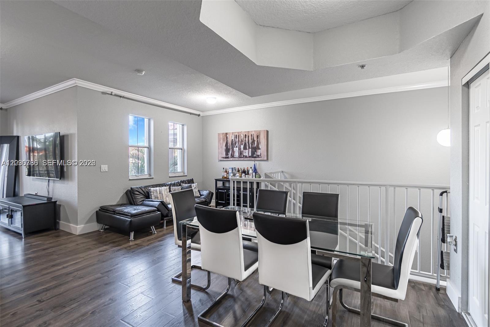 A dining area with a glass table and modern chairs sits adjacent to a living space — 6340 NW 114th Ave # 134, Doral FL 33178, DORAL, FL