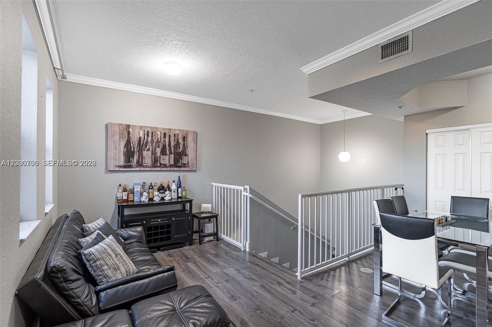 A living and dining area features dark wood flooring, a black leather sofa, and stairs — 6340 NW 114th Ave # 134, Doral FL 33178, DORAL, FL