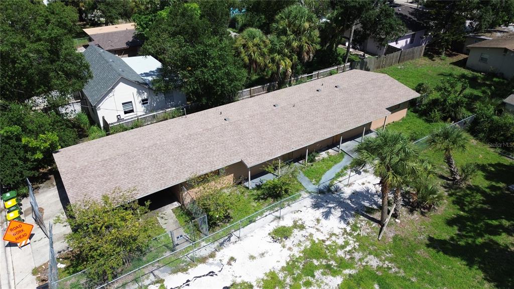 An aerial view shows a long, single-story building with a brown roof behind a fence — 1764 24TH STREET, SARASOTA, FL