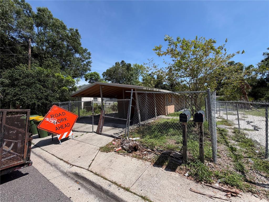 A chain-link fence surrounds a house with a carport and a road work sign — 1764 24TH STREET, SARASOTA, FL