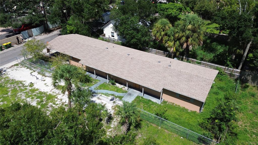 An aerial view of a long, single-story building with a shingled roof and fenced yard — 1764 24TH STREET, SARASOTA, FL