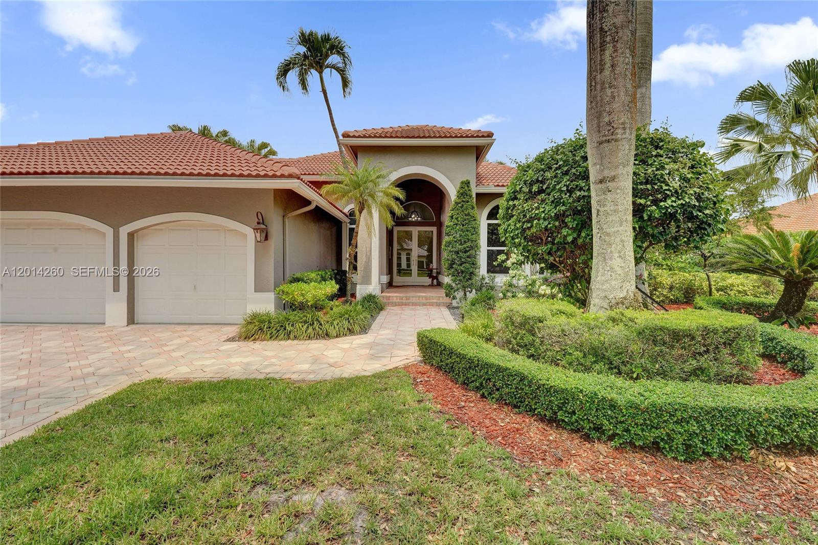 The exterior of a single-story house features a tiled roof, arched entryway, and paved driveway — 1640 Island Way, Weston FL 33326, WESTON, FL