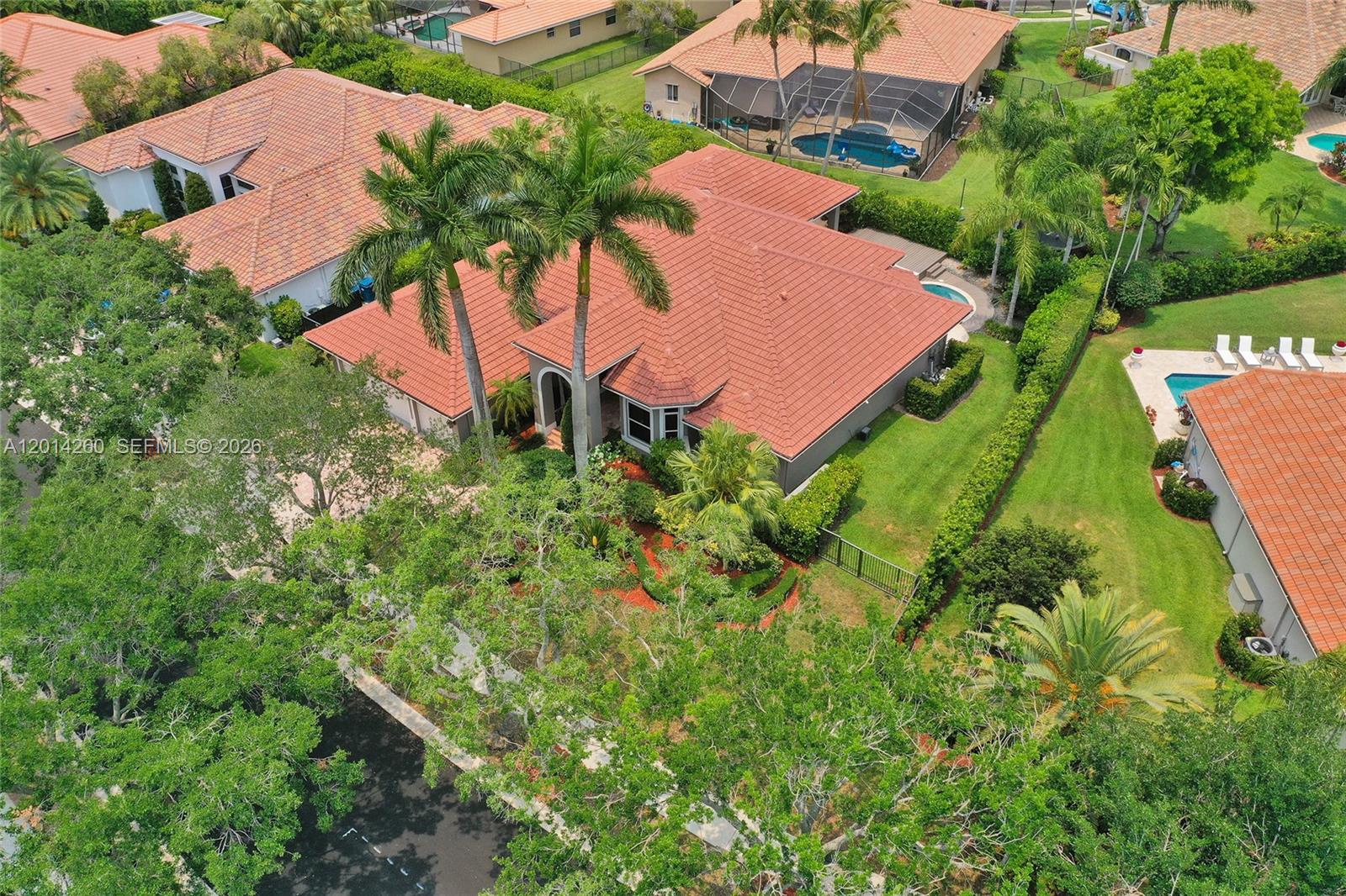 An aerial view shows a single-story house with a red tile roof and a pool — 1640 Island Way, Weston FL 33326, WESTON, FL