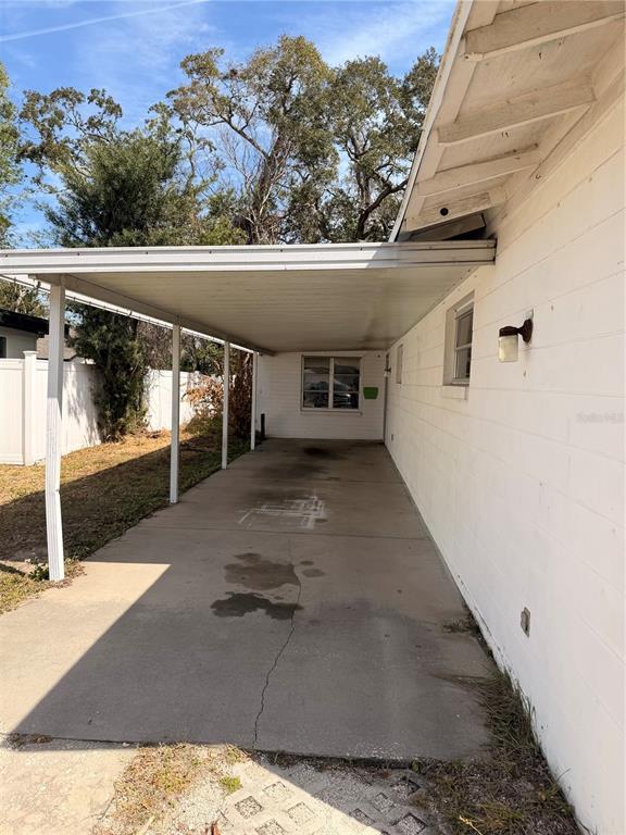 A concrete carport extends from the side of a white painted brick house — 1129 HOLLY AVENUE, DAYTONA BEACH, FL