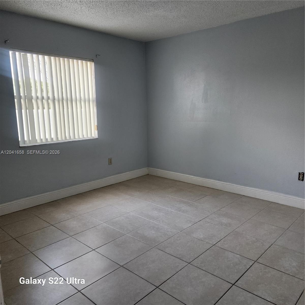 An empty room features light blue walls, white trim, and light-colored square floor tiles — 8200 SW 210th St # 111, Cutler Bay FL 33189, CUTLER BAY, FL