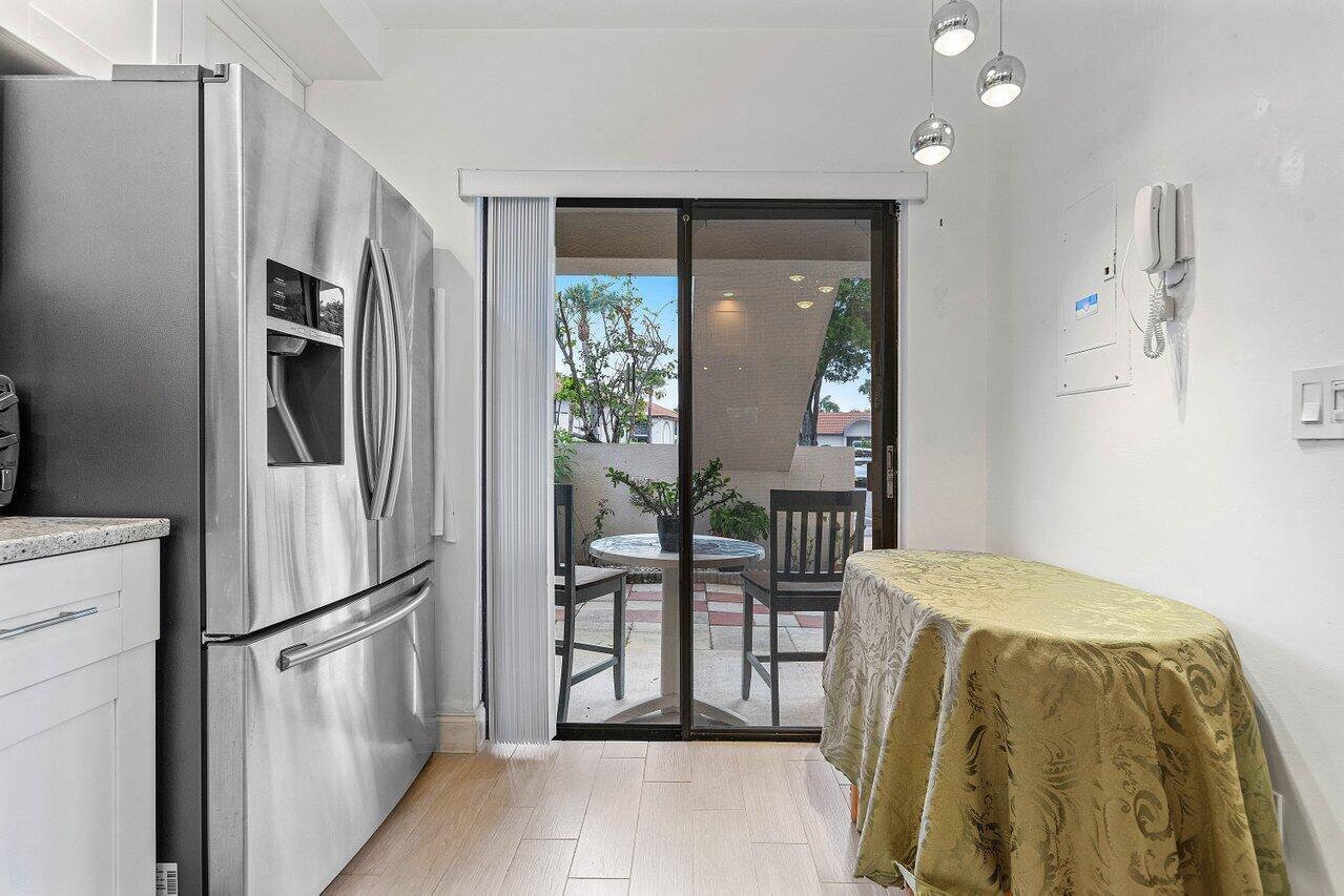 A kitchen with a stainless steel refrigerator, a small dining table, and a sliding glass door — 5200 E Club Circle # 106, Boca Raton FL 33487, BOCA RATON, FL