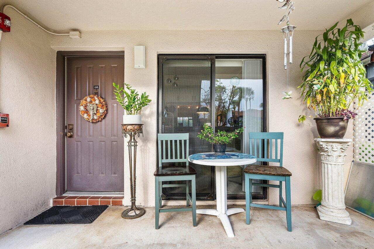 A patio features a brown door, a sliding glass door, and a small bistro set — 5200 E Club Circle # 106, Boca Raton FL 33487, BOCA RATON, FL