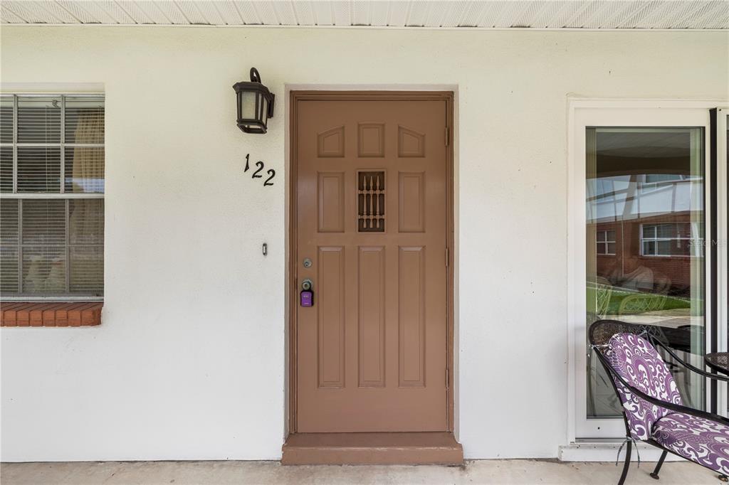 A brown front door with a small window sits on a white exterior wall — 650 PINELLAS POINT DRIVE S UNIT 122, ST PETERSBURG, FL