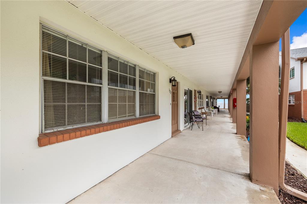 A long, covered concrete walkway runs along the exterior of a building with multiple unit doors — 650 PINELLAS POINT DRIVE S UNIT 122, ST PETERSBURG, FL