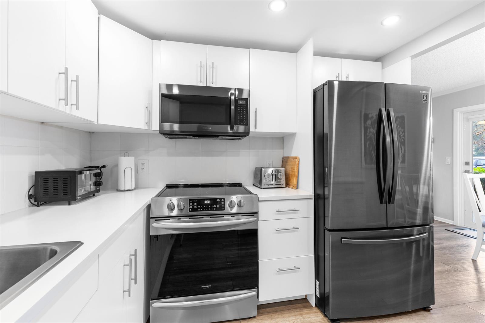 A kitchen features white cabinets, stainless steel appliances, a dark refrigerator, and white countertops — 1032 Ventnor H Crescent # H, Deerfield Beach FL 33442, DEERFIELD BEACH, FL