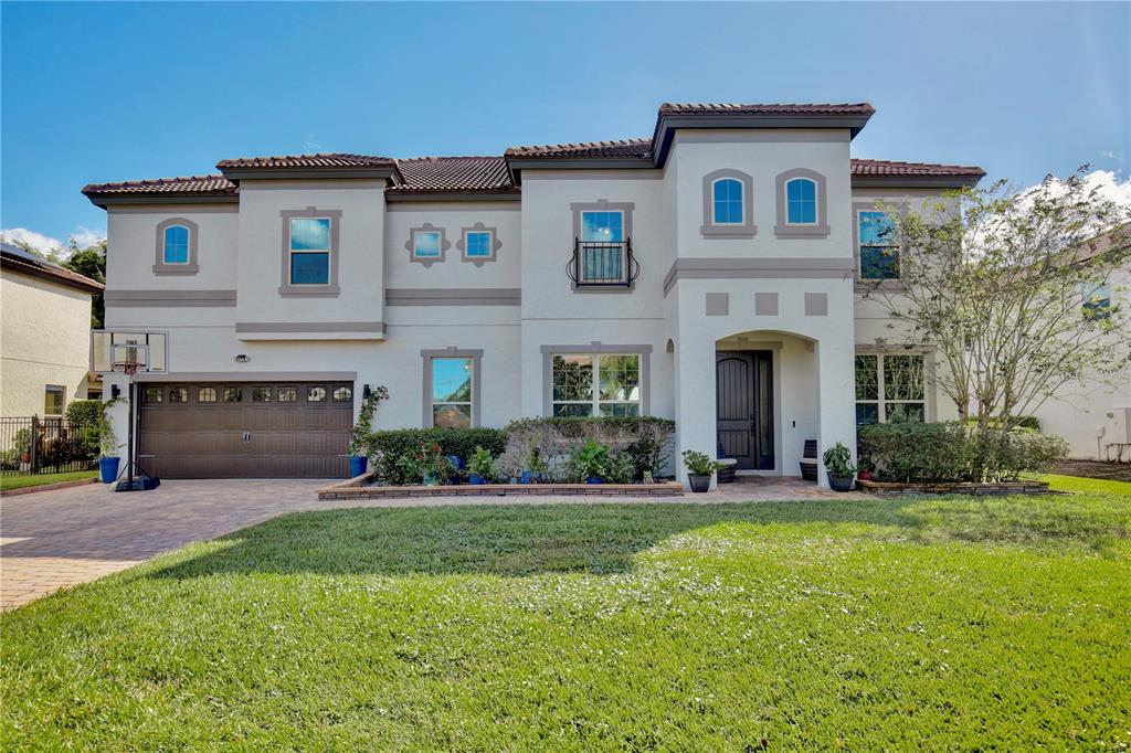 A two-story stucco house features a brown garage door, a front entrance, and a lawn — 450 TERRAVISTA PLACE, OVIEDO, FL
