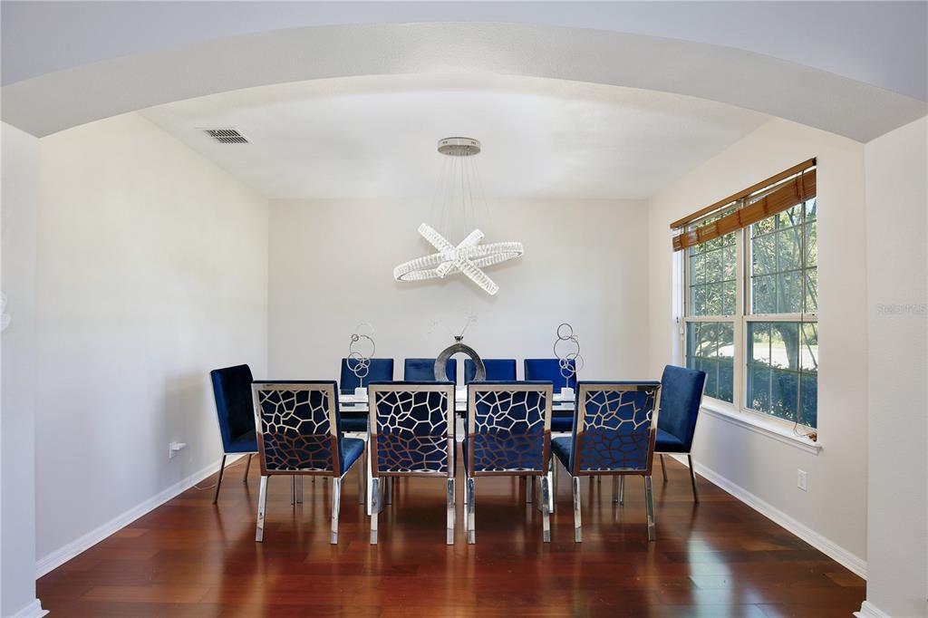 A dining room features a modern chandelier, blue velvet chairs, and dark hardwood floors — 450 TERRAVISTA PLACE, OVIEDO, FL