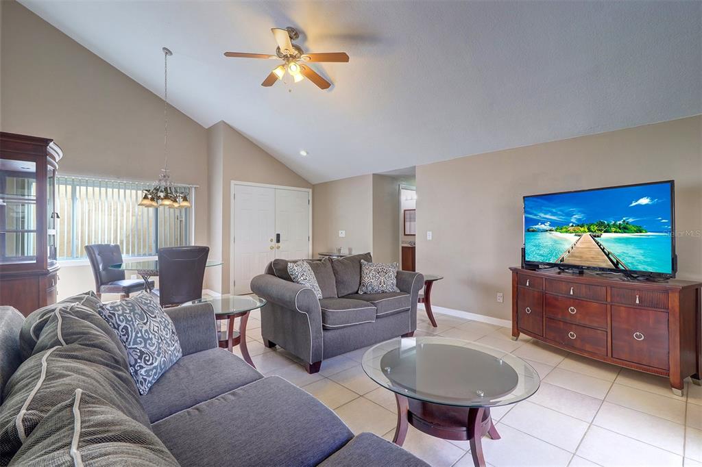 A living room with gray sofas, a glass coffee table, and a television on a cabinet — 4451 TIDAL POND ROAD, NEW PORT RICHEY, FL