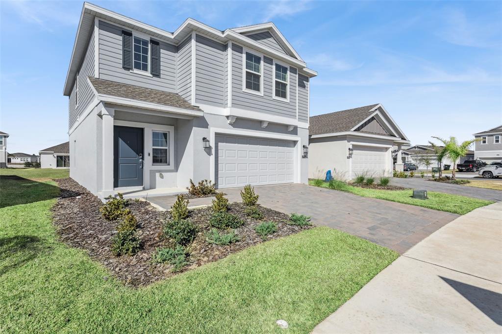 A two-story house with gray siding, a stucco lower level, and a paved driveway — 2916 TRANSFORMATION WAY, CLERMONT, FL