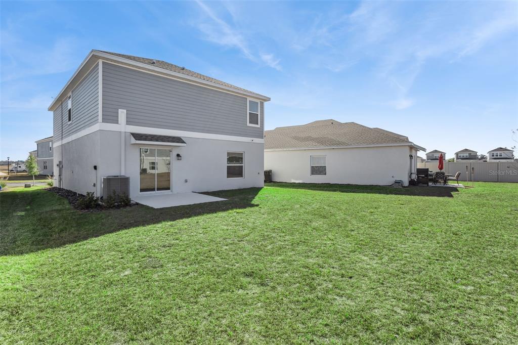 The exterior of a two-story house with a backyard, patio, and adjacent neighboring home — 2916 TRANSFORMATION WAY, CLERMONT, FL