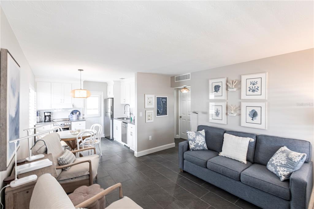 A living room with a blue sofa and tile floors opens into a white kitchen — 6020 MIDNIGHT PASS ROAD UNIT 31, SARASOTA, FL
