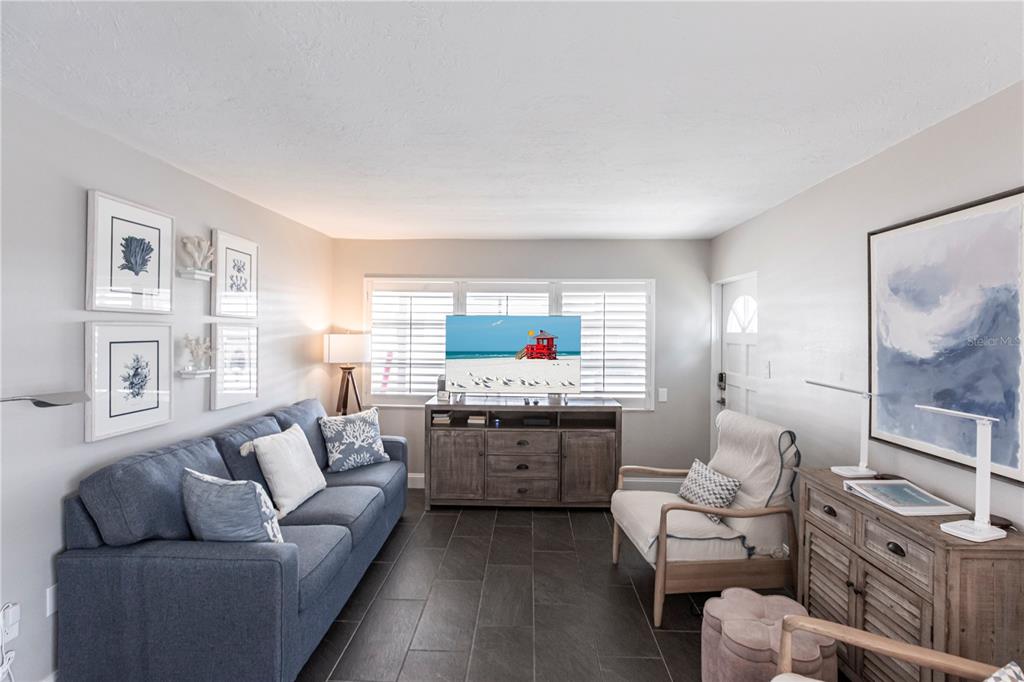 A living room features a blue sofa, a wooden media console, and a white armchair — 6020 MIDNIGHT PASS ROAD UNIT 31, SARASOTA, FL