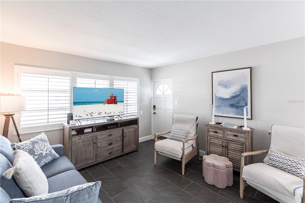 A living room features a blue sofa, two armchairs, a television console, and tile flooring — 6020 MIDNIGHT PASS ROAD UNIT 31, SARASOTA, FL