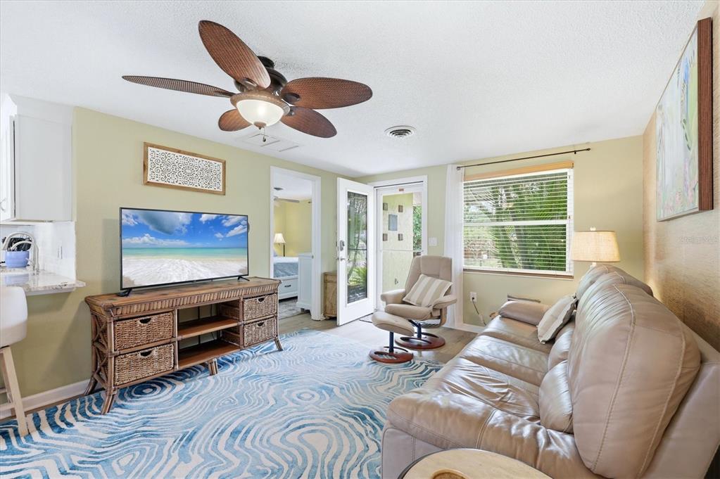 A living room features a tan leather sofa, wicker media console, and blue patterned rug — 4166 POMPANO ROAD, VENICE, FL