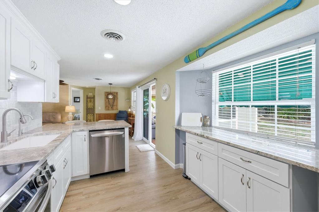 A kitchen features white cabinets, stainless steel appliances, light countertops, and a large window — 4166 POMPANO ROAD, VENICE, FL