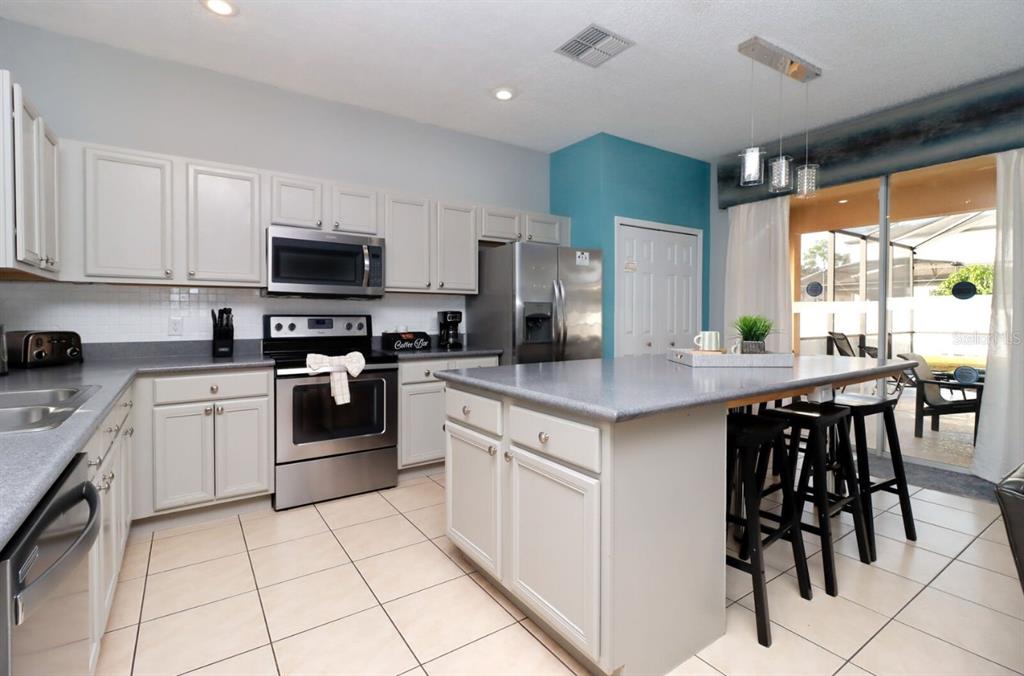 A kitchen with light-colored cabinets, stainless steel appliances, a center island, and tile flooring — 1315 SEASONS BOULEVARD, KISSIMMEE, FL