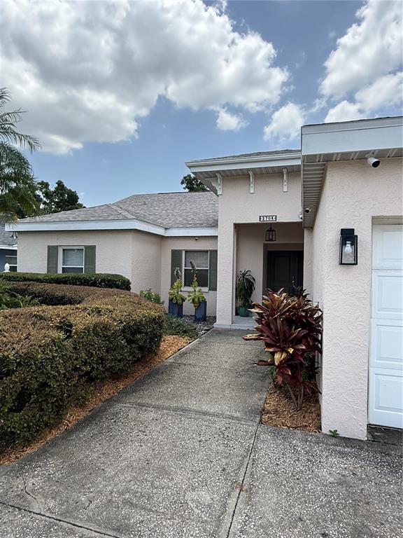 A tan house with a two-car garage and a large concrete driveway under a blue sky — 2708 W OSBORNE AVENUE, TAMPA, FL