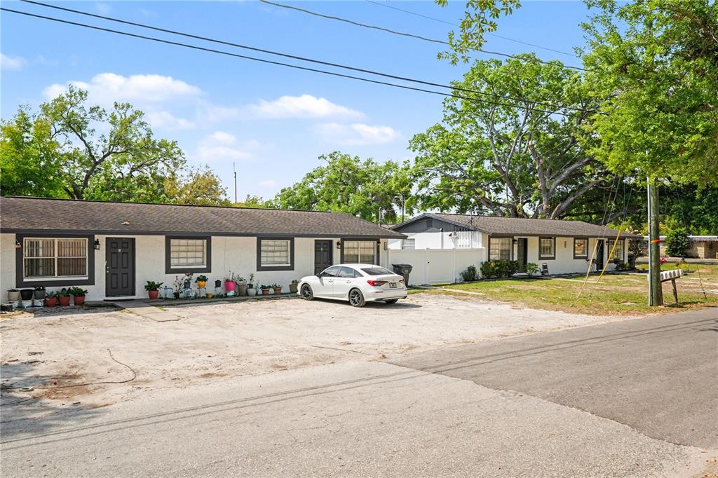 A single-story residential building with a gravel parking area and a white sedan parked outside — 14207 N 12TH STREET UNIT A, TAMPA, FL