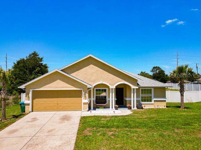 A tan, single-story suburban house with a two-car garage and a front porch — 13338 SW 48TH AVENUE, OCALA, FL