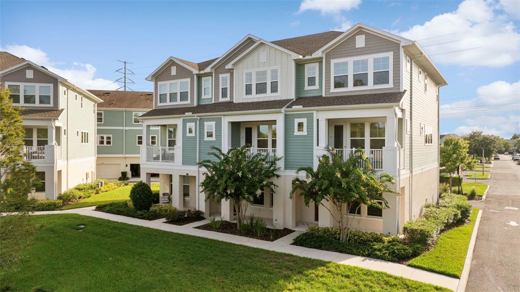 A multi-story townhouse complex with light green siding, white trim, and elevated balconies — 9533 CAVENDISH DRIVE, TAMPA, FL