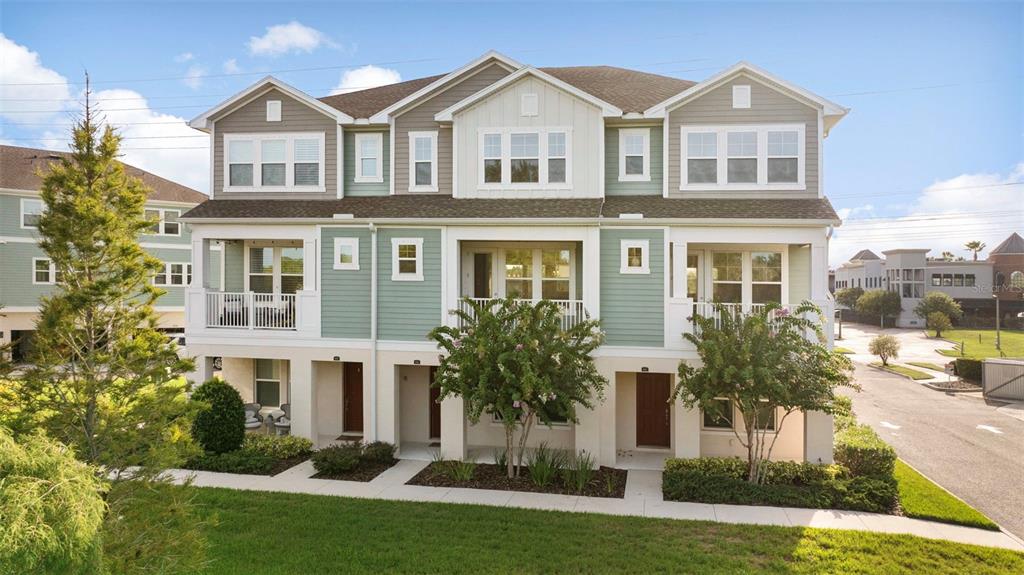 A three-story townhouse with light green siding, white trim, and balconies on the second level — 9533 CAVENDISH DRIVE, TAMPA, FL