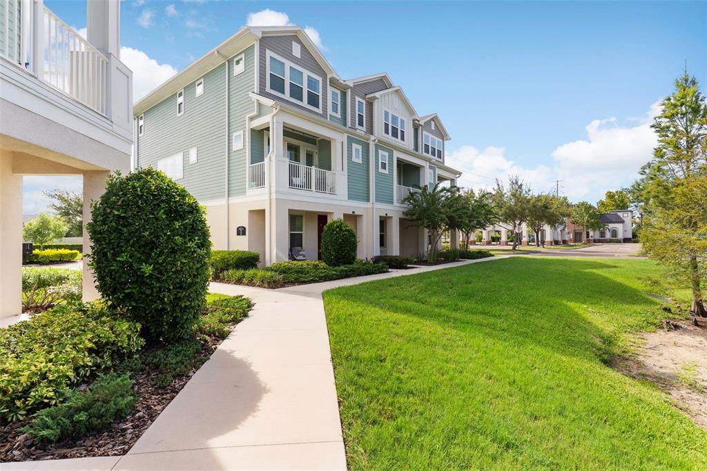A multi-story residential building with light green siding features balconies and a concrete walkway — 9533 CAVENDISH DRIVE, TAMPA, FL