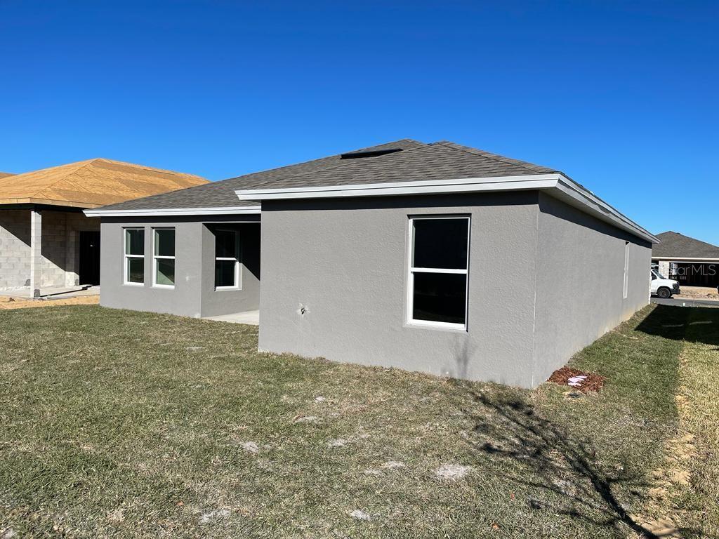 The exterior of a gray stucco house with a shingled roof and a grassy yard — 1186 TUPELO TRAIL, HAINES CITY, FL