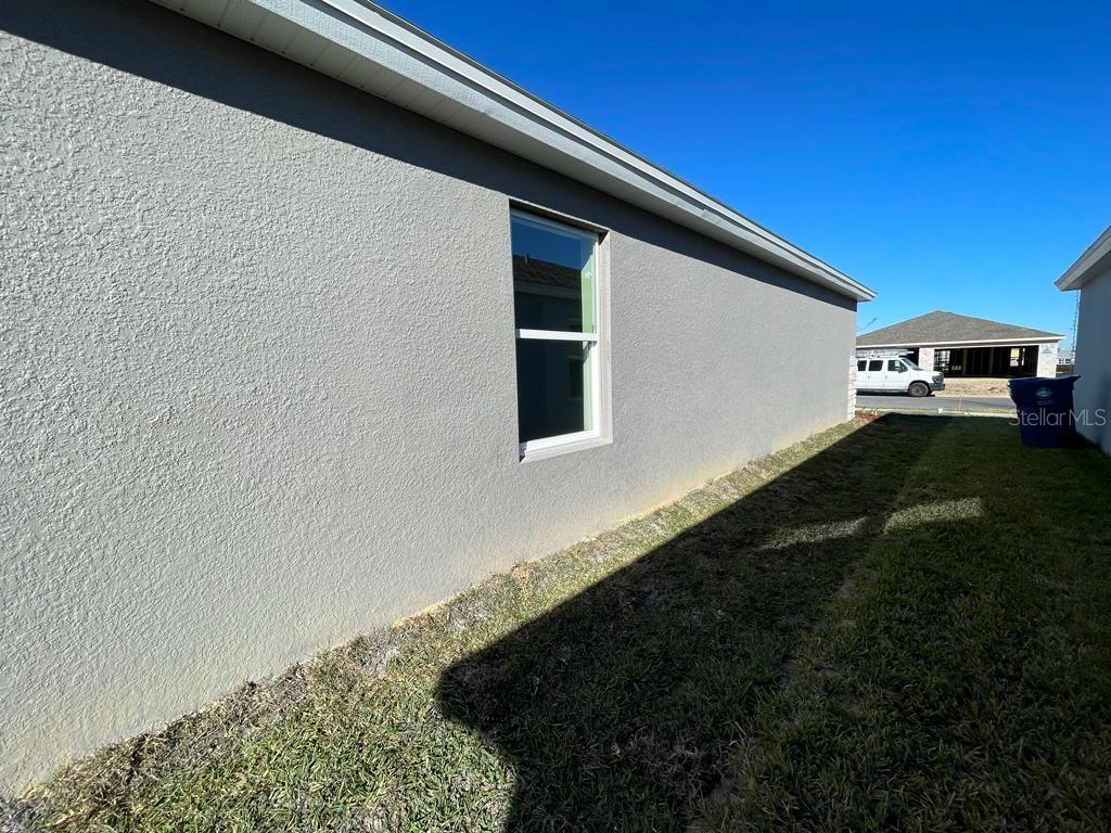 The exterior side wall of a house features a single window and a grassy yard — 1186 TUPELO TRAIL, HAINES CITY, FL