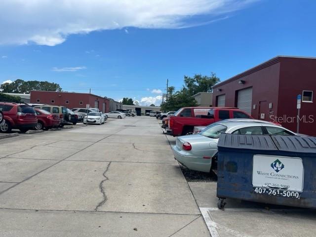 A paved parking lot between two commercial buildings with several parked vehicles and a dumpster — 145 RONNING WAY, LONGWOOD, FL