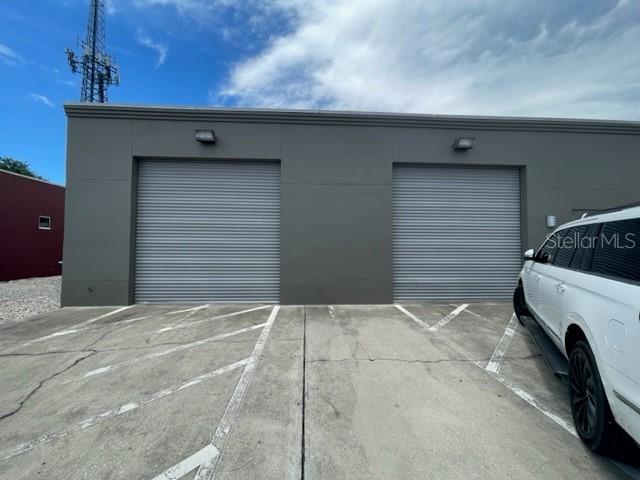 A gray commercial building exterior features two roll-up garage doors and a parked white SUV — 145 RONNING WAY, LONGWOOD, FL