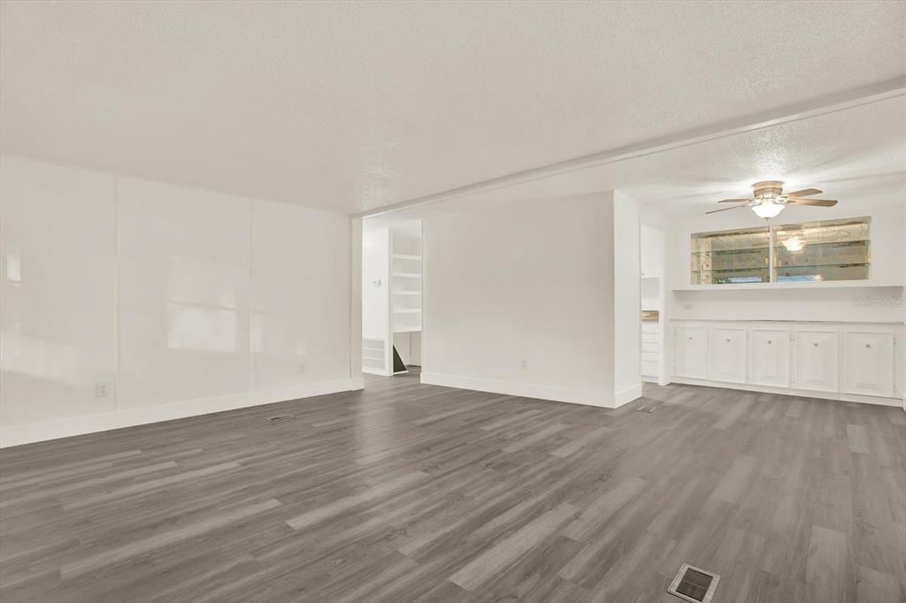 A living room features gray wood-look flooring, white walls, and a ceiling fan — 10051 HUNTLEY STREET, NEW PORT RICHEY, FL