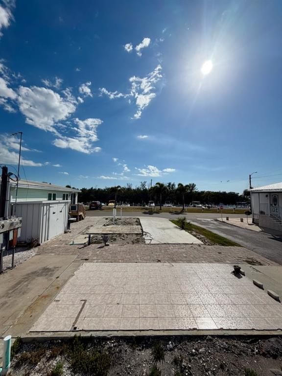 A vacant lot with a tiled patio area and a small shed under a sunny sky — 10315 CORTEZ ROAD W UNIT 2-4, BRADENTON, FL