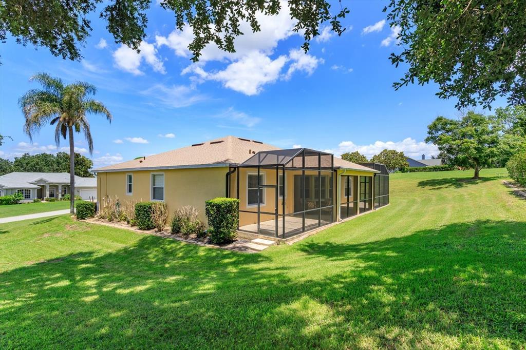 A yellow house with a screened-in lanai sits on a large, grassy lot — 12560 KATHERINE CIRCLE, CLERMONT, FL