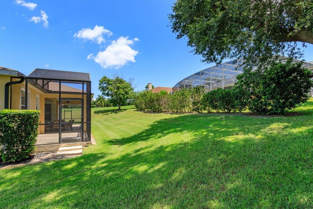 A backyard features a screened-in patio, a grassy lawn, and a neighboring pool enclosure — 12560 KATHERINE CIRCLE, CLERMONT, FL