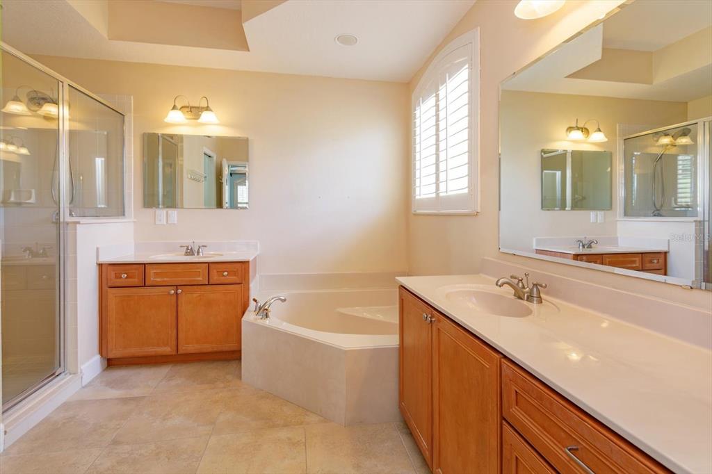 A bathroom features a soaking tub, dual vanities with wood cabinets, and a glass shower — 12560 KATHERINE CIRCLE, CLERMONT, FL