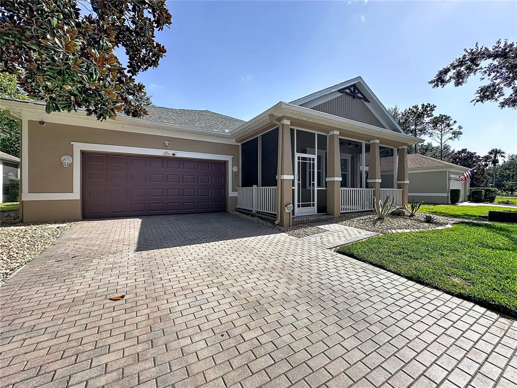 A tan house with a dark garage door and a screened-in front porch — 157 CREPE MYRTLE DRIVE, GROVELAND, FL