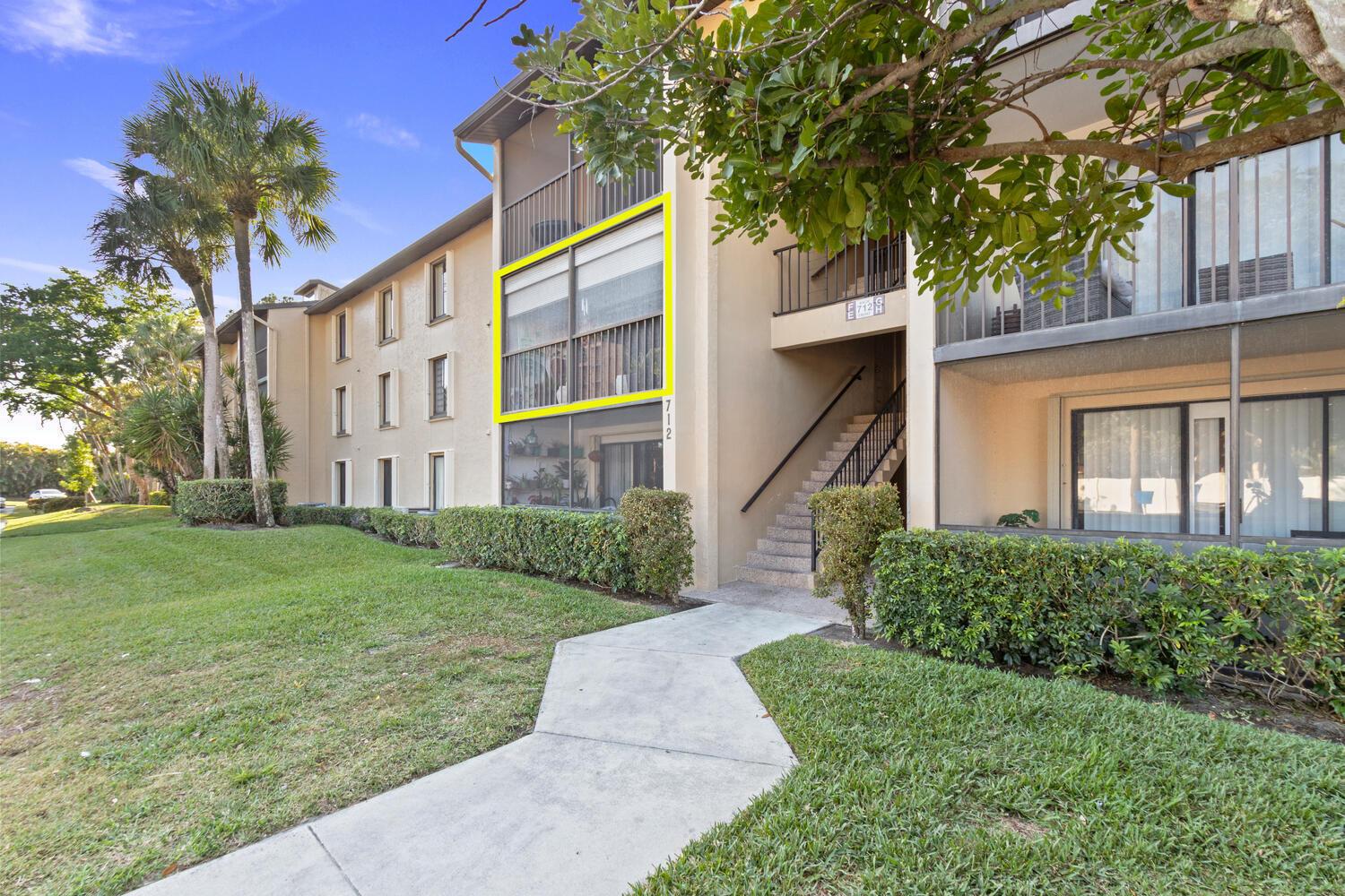 An exterior view of a multi-story apartment building with a highlighted second-floor screened balcony — 712 Sunny Pine Way # E2, FL 33415, FL
