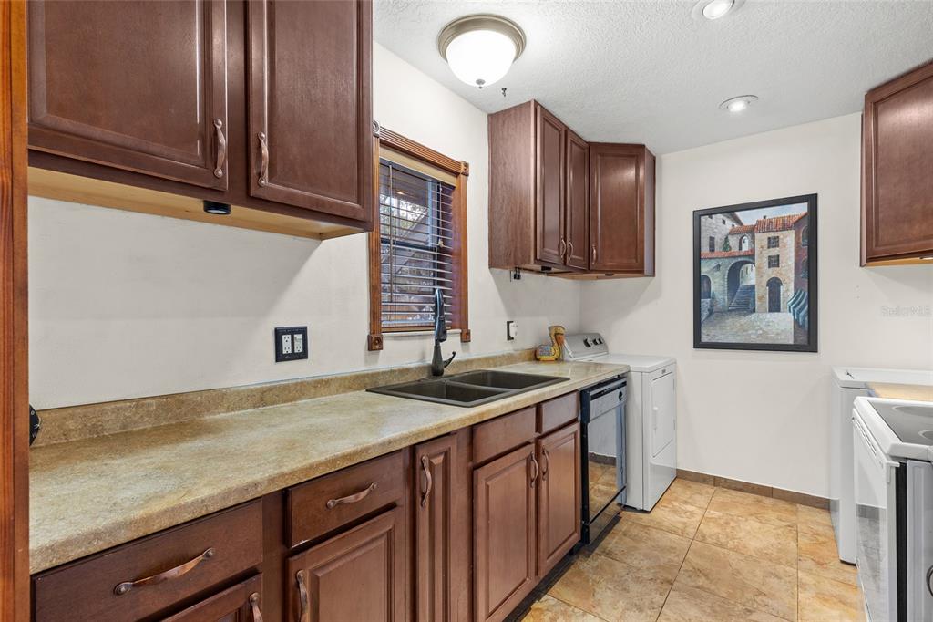 A laundry room featuring dark wood cabinets, a sink, and tile flooring — 4340 AQUA VISTA DRIVE UNIT A, ORLANDO, FL