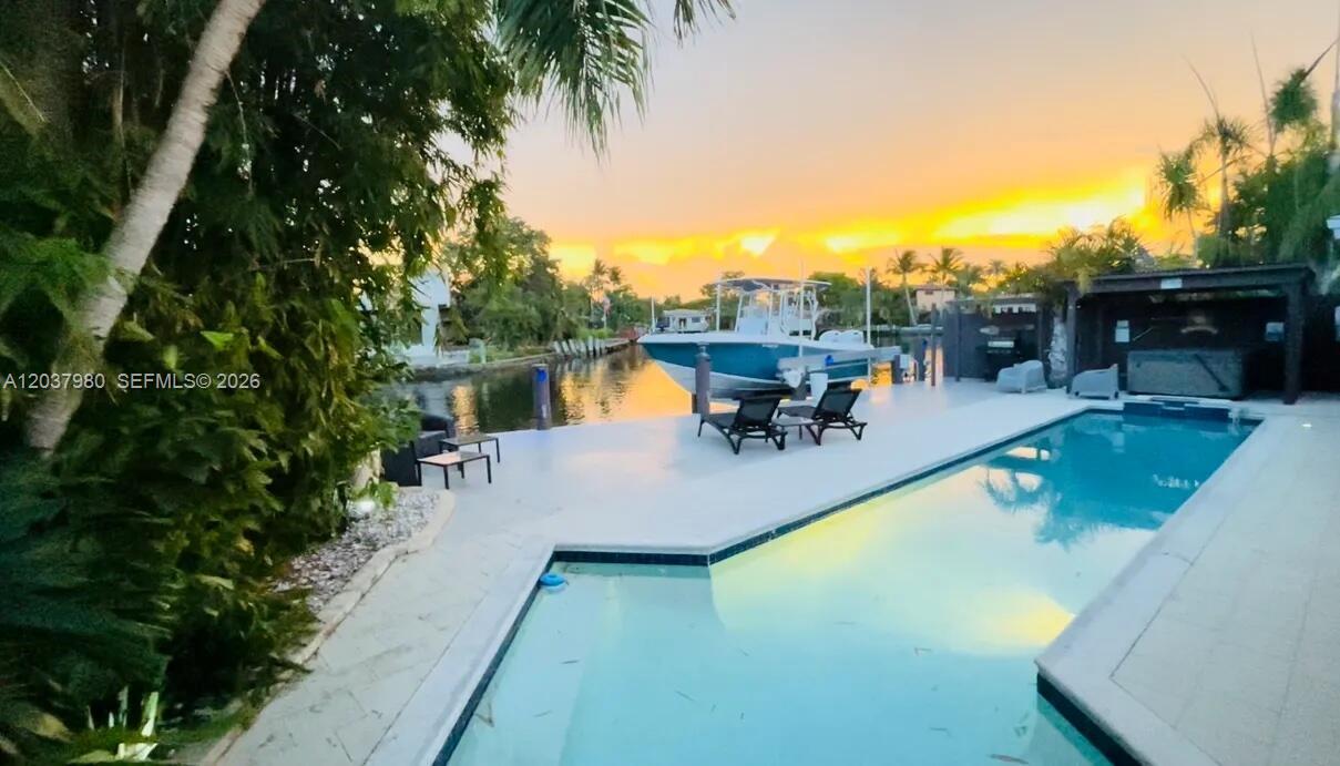 A swimming pool sits on a patio next to a canal with a docked boat — 2100 NE 24th St, Wilton Manors FL 33305, WILTON MANORS, FL