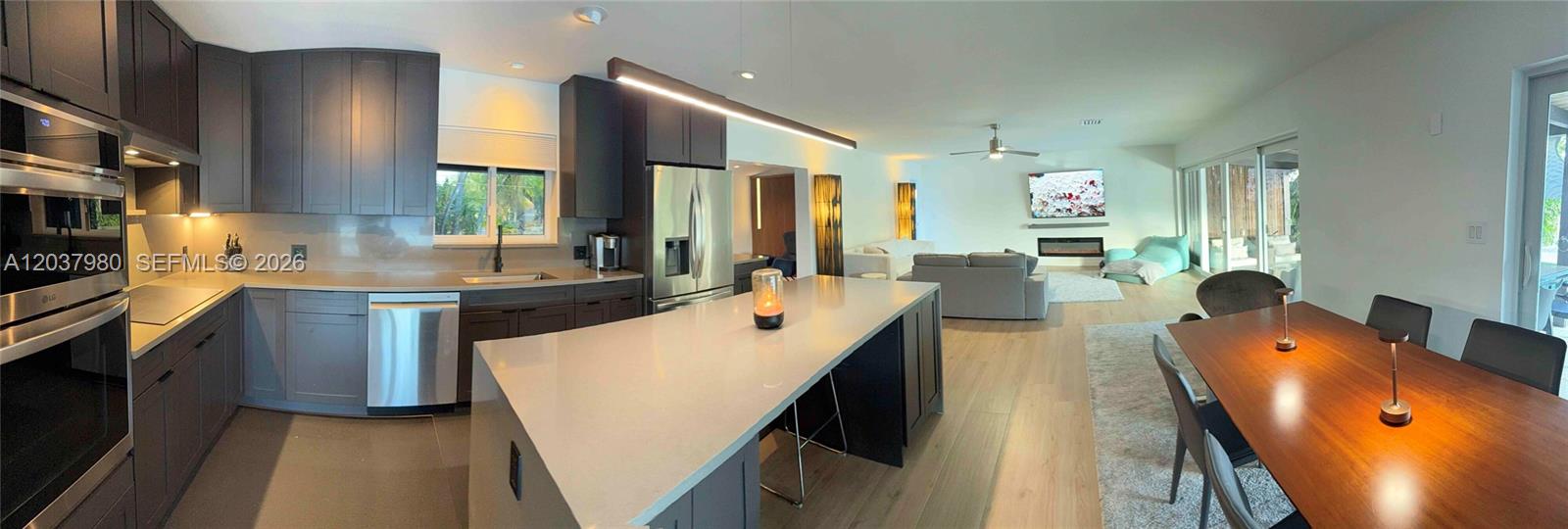A modern open-concept kitchen with dark cabinetry and a large island overlooks a living area — 2100 NE 24th St, Wilton Manors FL 33305, WILTON MANORS, FL