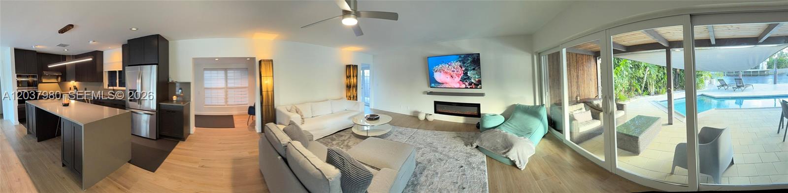 A panoramic view of a modern living room and kitchen opening to a pool patio — 2100 NE 24th St, Wilton Manors FL 33305, WILTON MANORS, FL