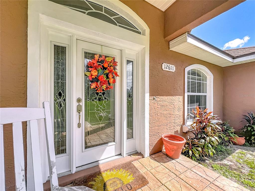 A white front door with a glass insert and a wreath sits on a porch — 12611 NE 36TH AVENUE, ANTHONY, FL
