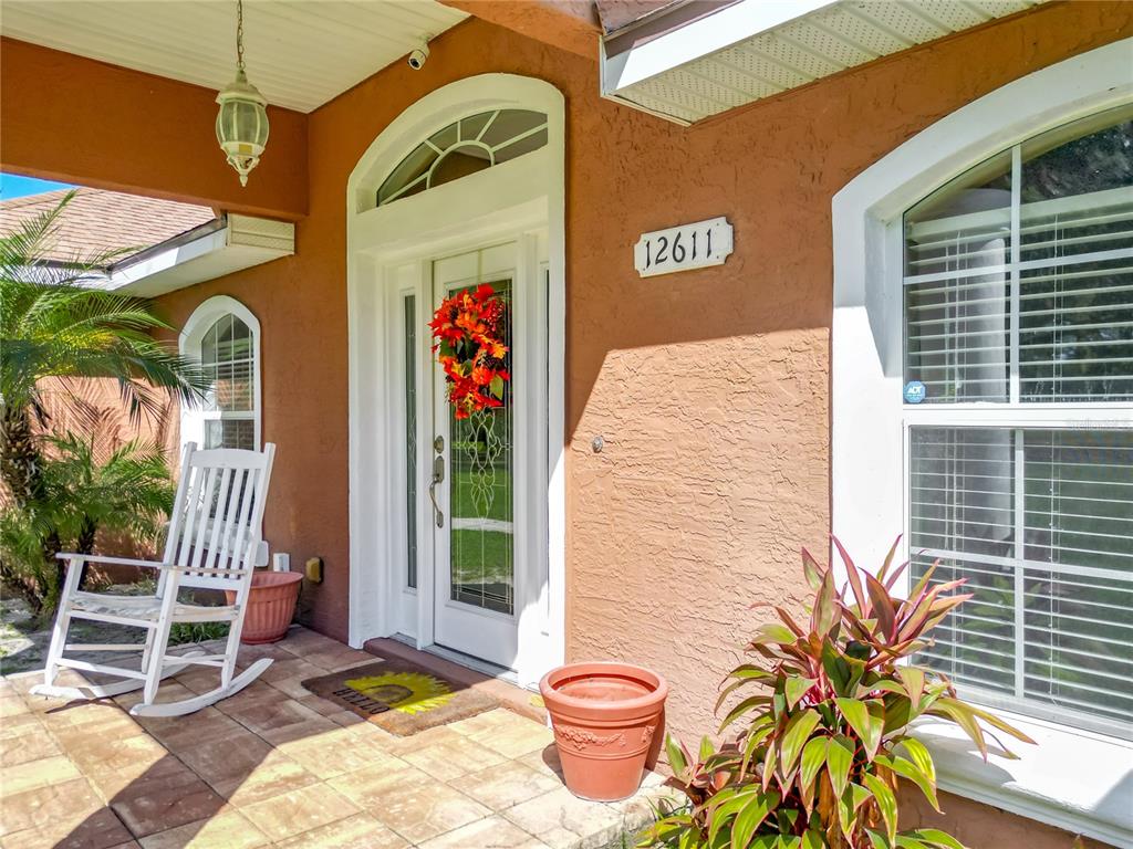 A front porch features a white rocking chair, a potted plant, and a front door — 12611 NE 36TH AVENUE, ANTHONY, FL